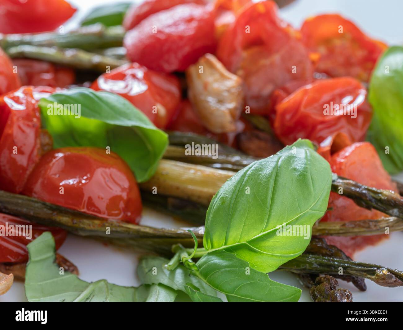 Asperges grillées savoureuses avec tomates mûres et feuilles de basilic frais, une option végétarienne parfaite pour les mangeurs soucieux de leur santé. Banque D'Images