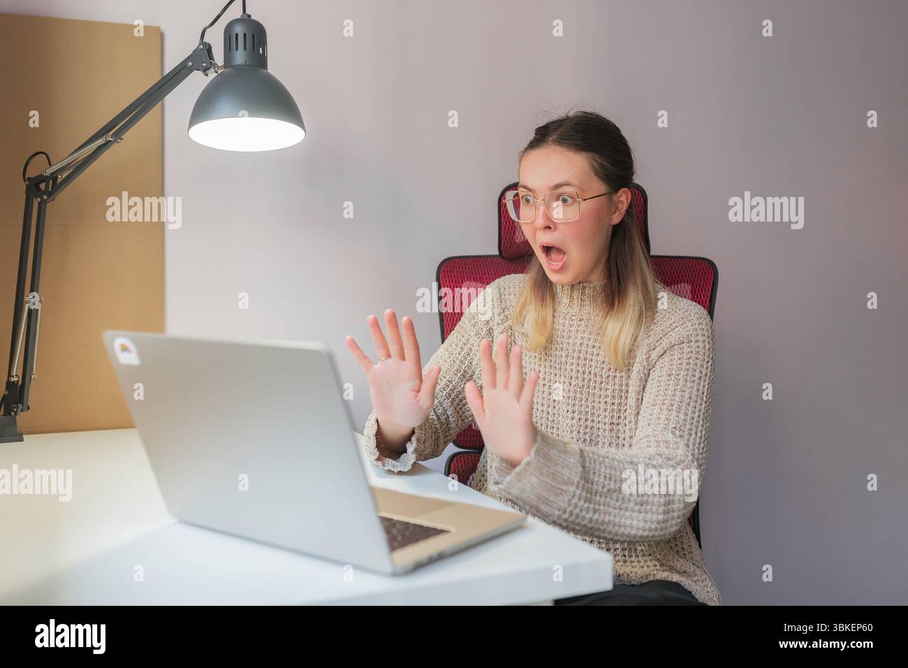Femme surprise avec les mains levées, regardant l'écran d'ordinateur portable pendant le moment de travail à distance. Expression choquée, les paumes vers le haut, la bouche et les yeux grands ouverts, si Banque D'Images