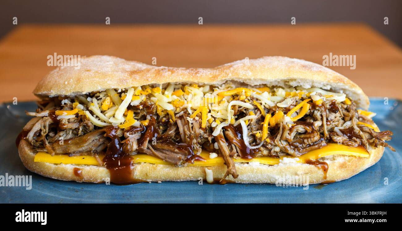 Sandwich au porc effiloché copieux avec fromage fondu et sauce barbecue Banque D'Images