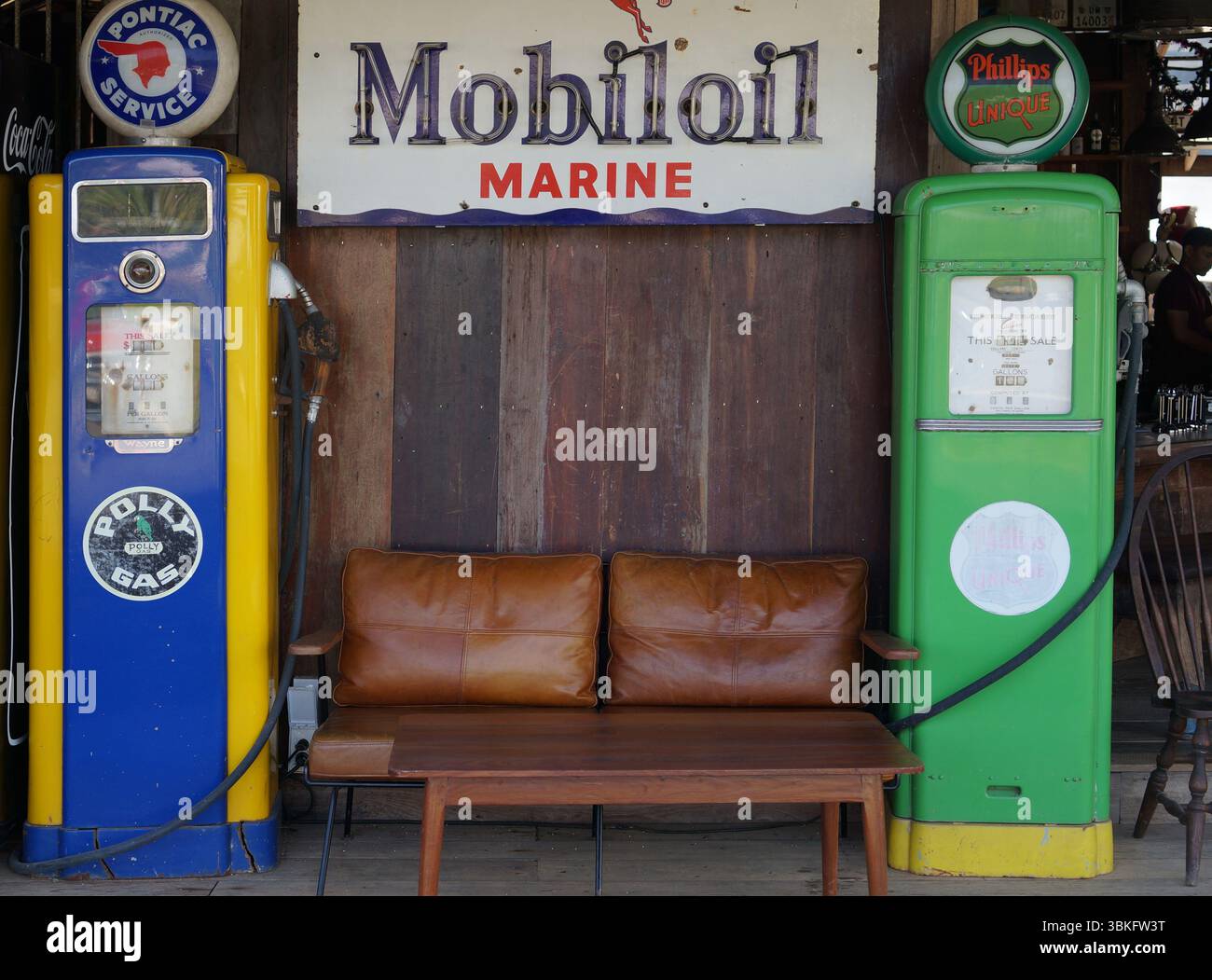 Une scène nostalgique avec deux pompes à essence classiques, un panneau d'huile et un banc en bois, évoque le charme d'une époque révolue. Banque D'Images