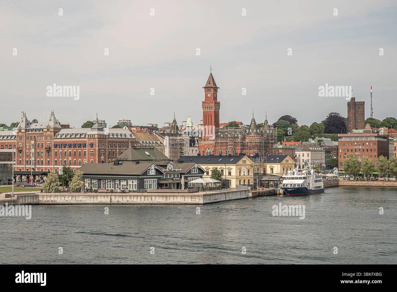 Ferry amarré au port de Helsingborg, Suède avec l'emblématique hôtel de ville en briques rouges et les bâtiments historiques du front de mer en vue, Suède, 15 juin 2025 Banque D'Images