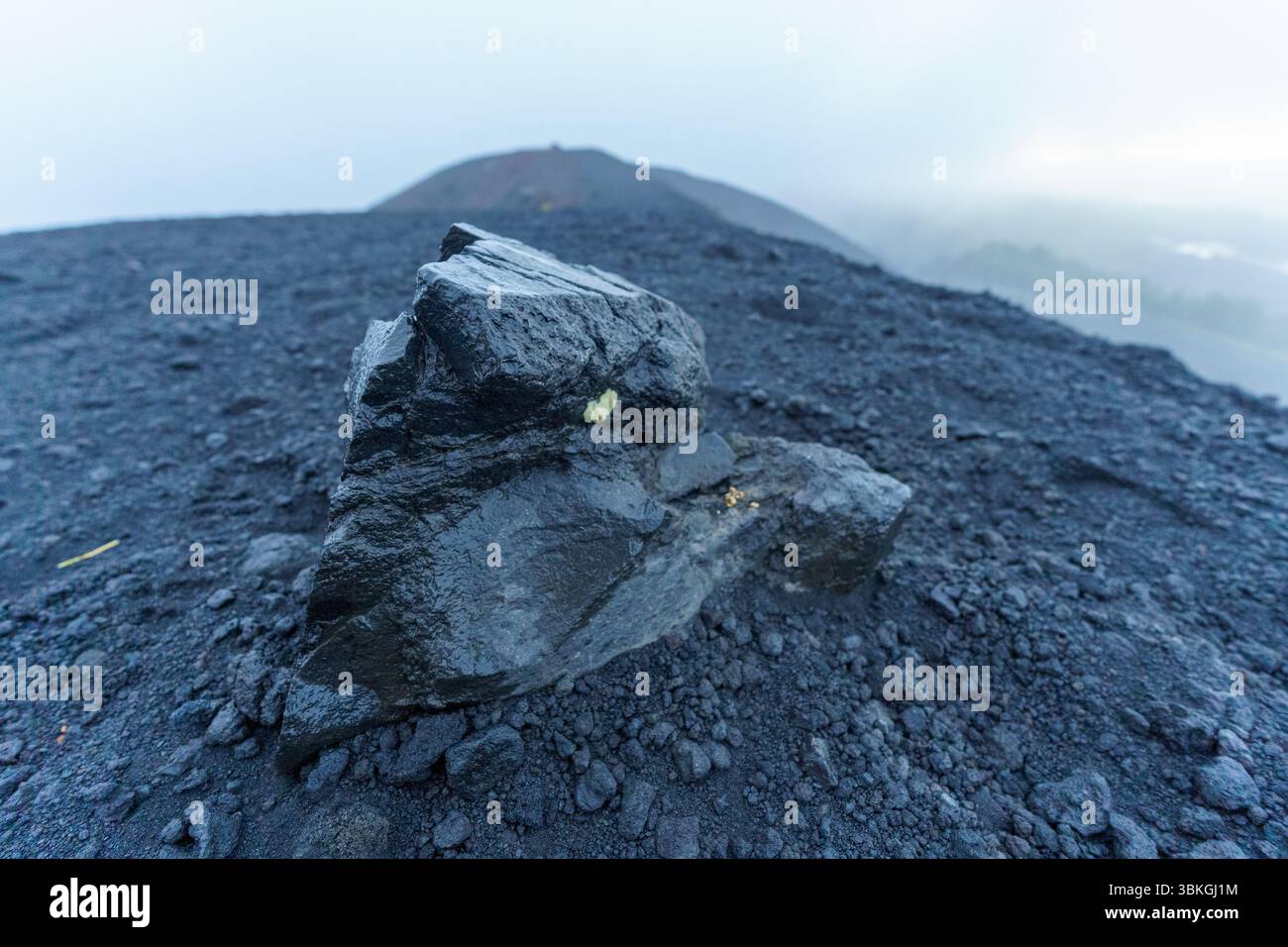 Gros plan d'une pierre de lave noire se trouvant dans les cendres d'anciennes éruptions volcaniques sur l'Etna en Sicile, Italie Banque D'Images