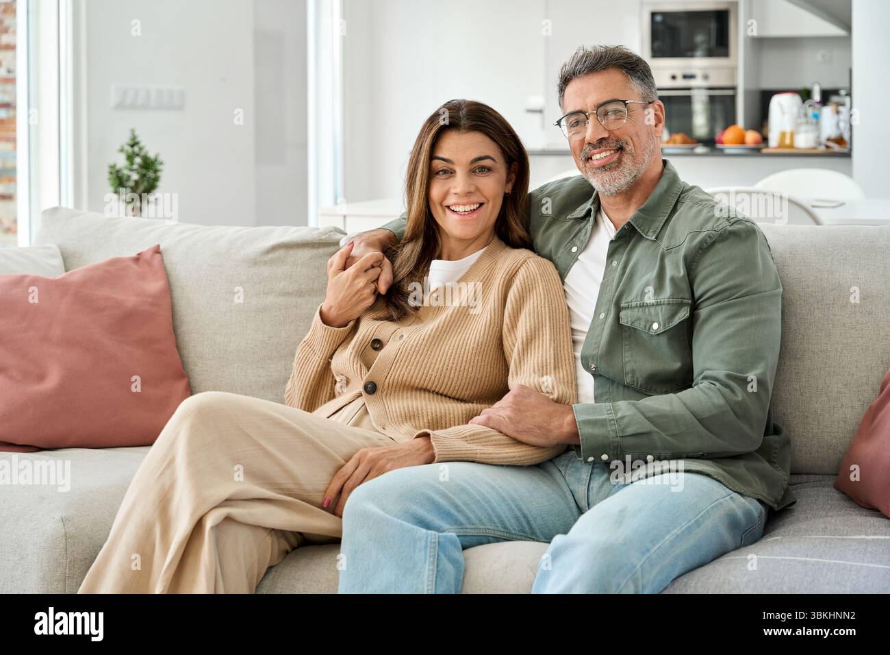 Heureux couple romantique mature d'âge moyen serrant assis sur le canapé à la maison. Banque D'Images
