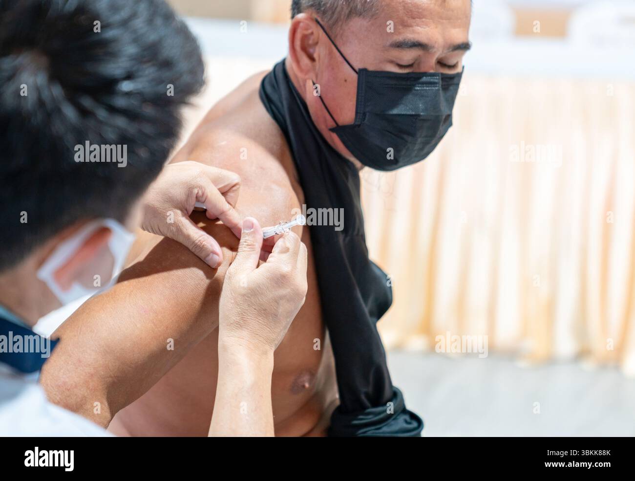 Un travailleur âgé se voit administrer un vaccin contre la grippe dans le cadre d'une initiative de santé de l'entreprise. Banque D'Images
