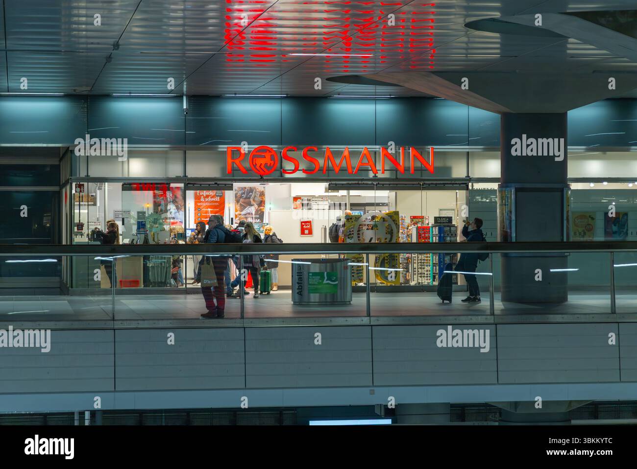 Logo rouge vif 'ROSSMANN' au-dessus d'une pharmacie animée dans un cadre intérieur moderne avec des acheteurs. Scène de détail et de commerce. Berlin, Allemagne. 30 mars Banque D'Images