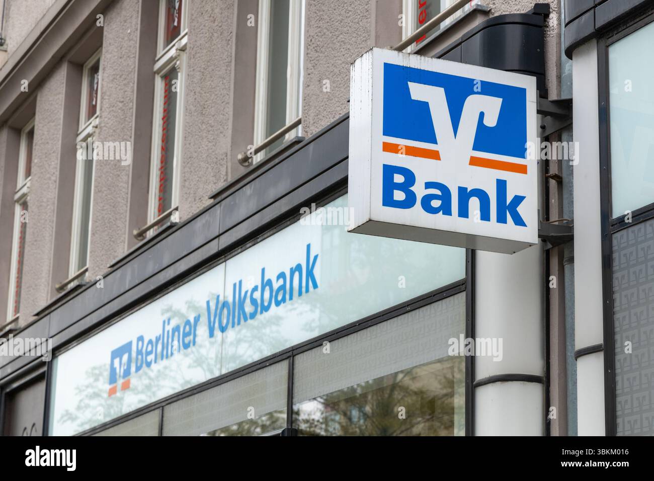 Signalisation bleue et blanche Berliner Volksbank à l'extérieur du bâtiment. Le logo « V-Bank » est bien visible. Institution financière en milieu urbain. Berlin, G. Banque D'Images