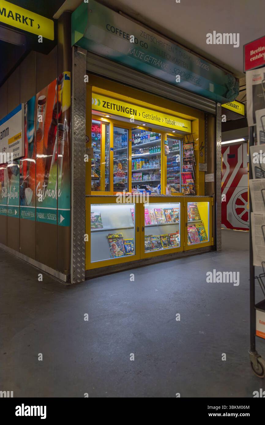Kiosque jaune dans une station de métro vendant des journaux ('Zeitungen'), des boissons ('Getränke') et du tabac ('Tabak'). Commodité urbaine et nécessités quotidiennes Banque D'Images
