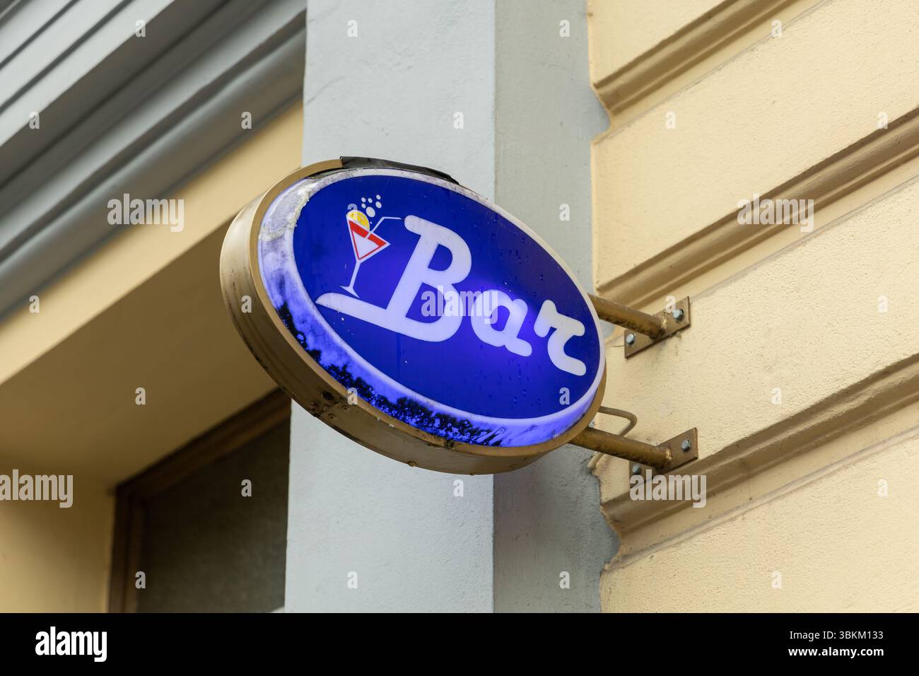 Panneau lumineux de style vintage monté sur le mur d'un bâtiment à Berlin, avec fond bleu et verre à cocktail emblématique, invitant les clients à prendre un verre Banque D'Images