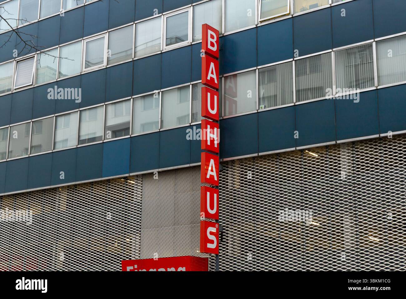 Un grand bâtiment gris Bauhaus avec un panneau vertical rouge affichant le nom de l'entreprise. Architecture moderne et concept de vente au détail. Berlin, Allemagne. 29 mars Banque D'Images
