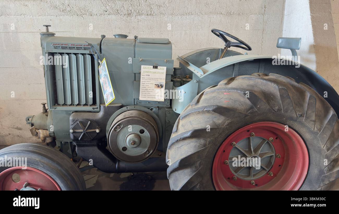 Un tracteur gris vintage est partiellement visible, avec un accent sur le pneu avant et le grand pneu arrière. Un panneau est fixé à la carrosserie du tracteur. Banque D'Images