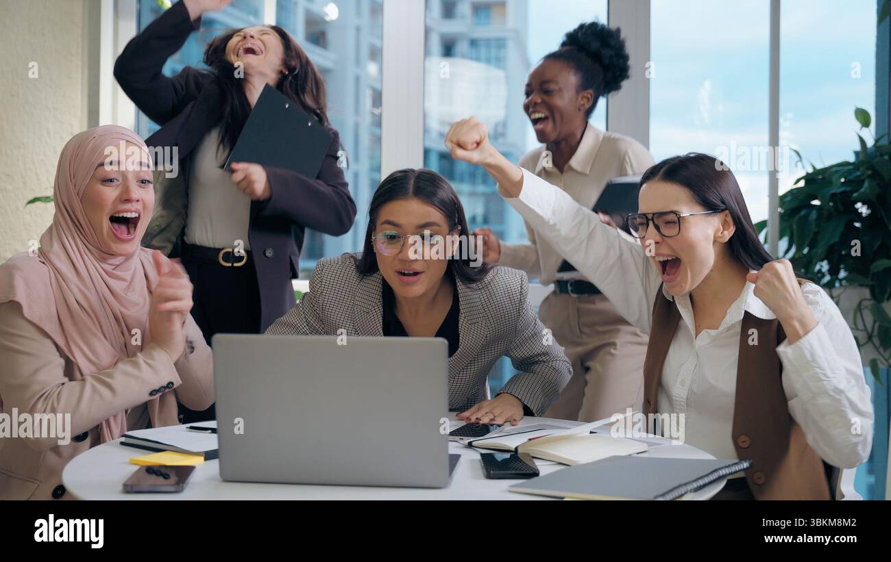 Excité choqué multiethnique femmes femmes d'affaires collègues groupe multiracial cherchant ordinateur portable célébrant l'offre d'affaires de choc gagnant Banque D'Images