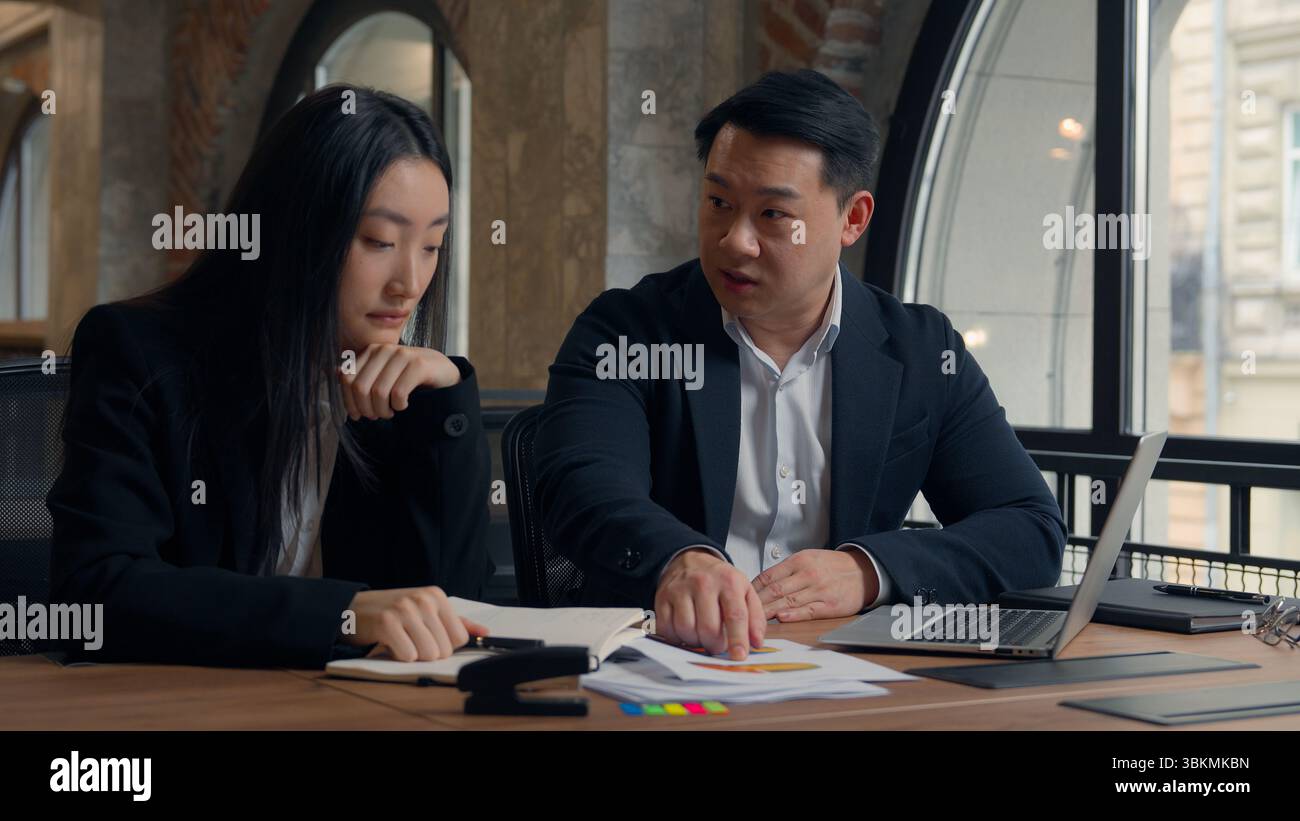 Mauvais résultat commercial problème deux collègues du bureau mécontents PDG patron asiatique homme d'affaires coréen dirigeant pointant vers des papiers d'ordinateur portable Banque D'Images