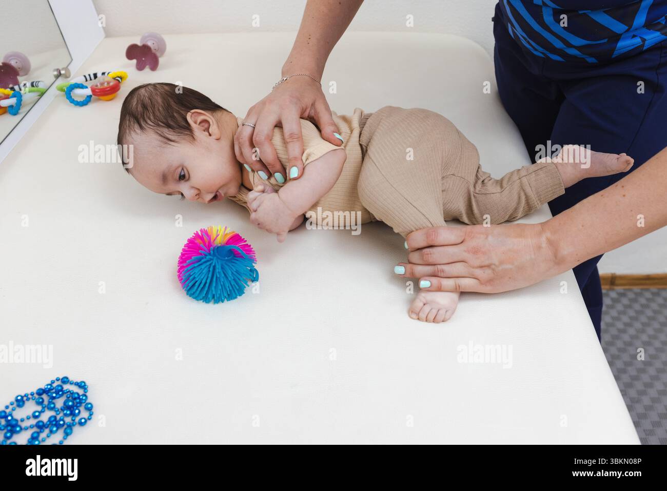 Le physiothérapeute aide l'enfant avec le retournement en corrigeant le mouvement des jambes pendant la séance de thérapie. Survol du développement des compétences Banque D'Images
