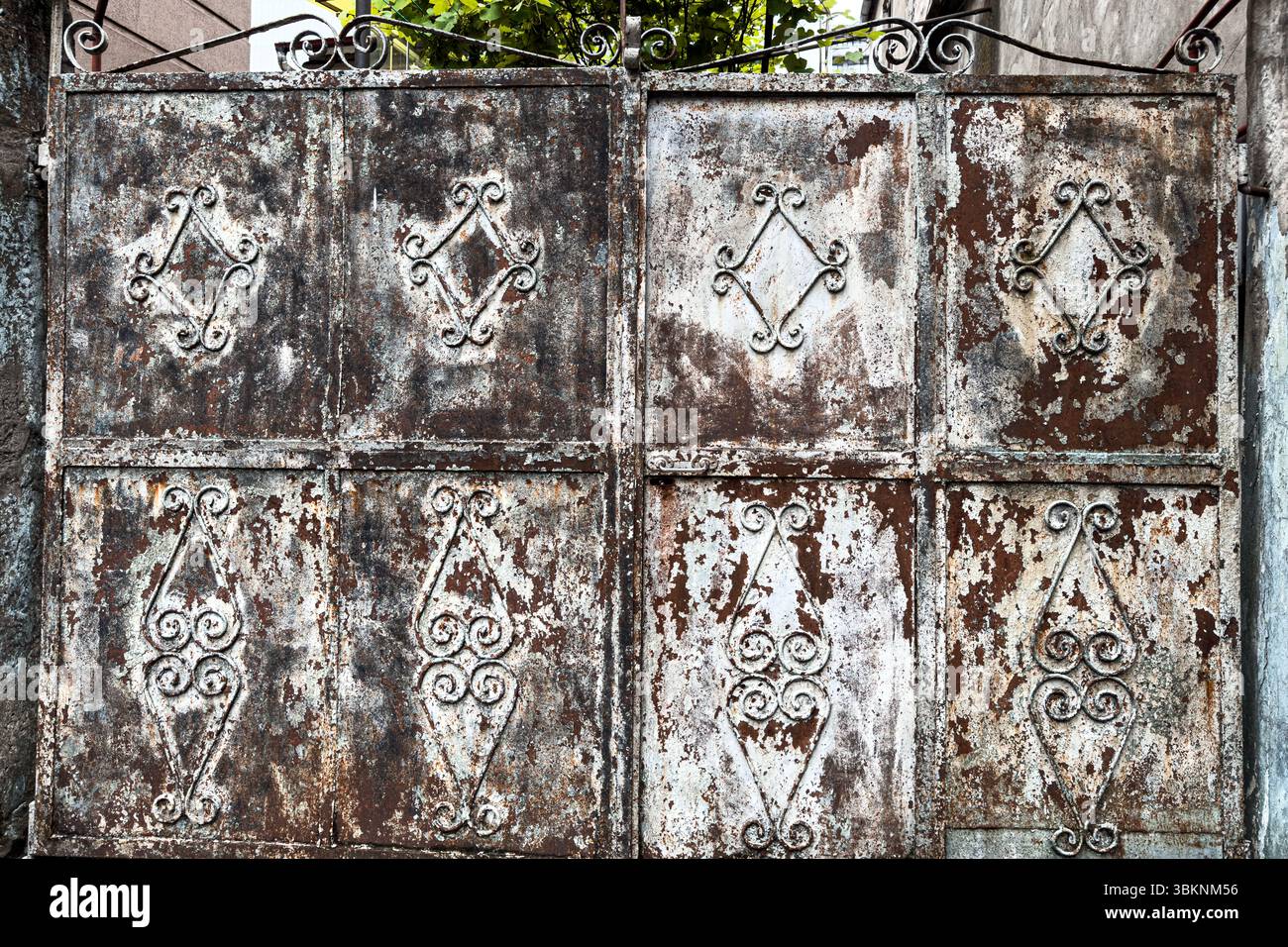 Portail en fer forgé rouillé avec motifs géométriques décoratifs et texture métallique altérée. Détail grunge, adapté aux arrière-plans. Personne. Banque D'Images