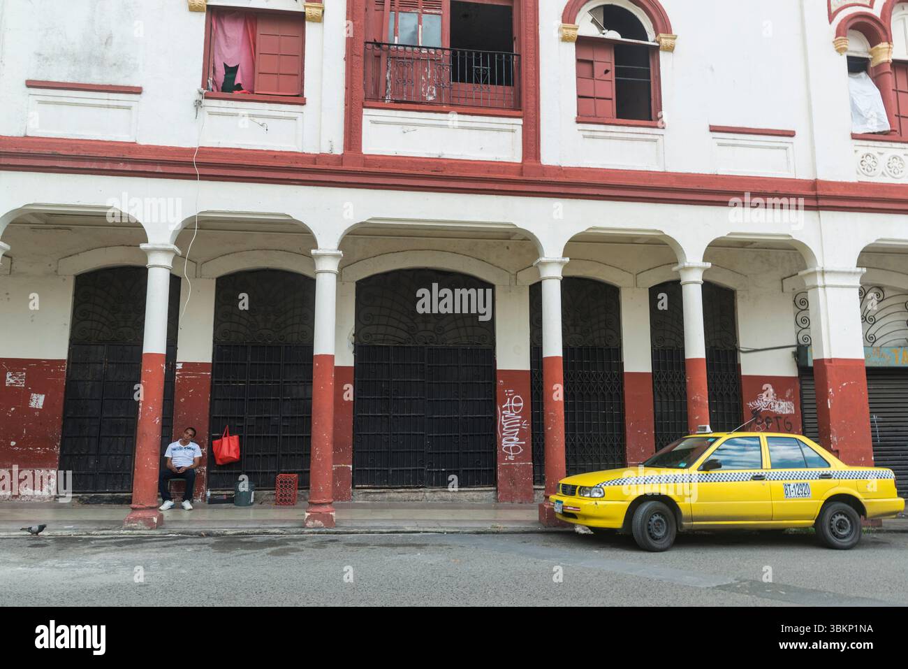 Taxi jaune en face de l'ancien bâtiment délabré avec galerie à Casco Viejo, Panama City, Panama. Banque D'Images