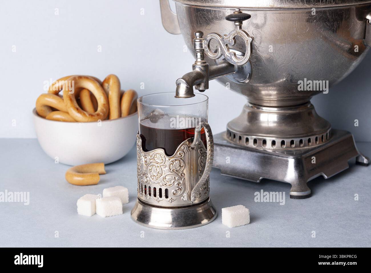 Un verre de thé dans un porte-gobelet en métal se tient sous le robinet d'un samovar, sur la table Banque D'Images
