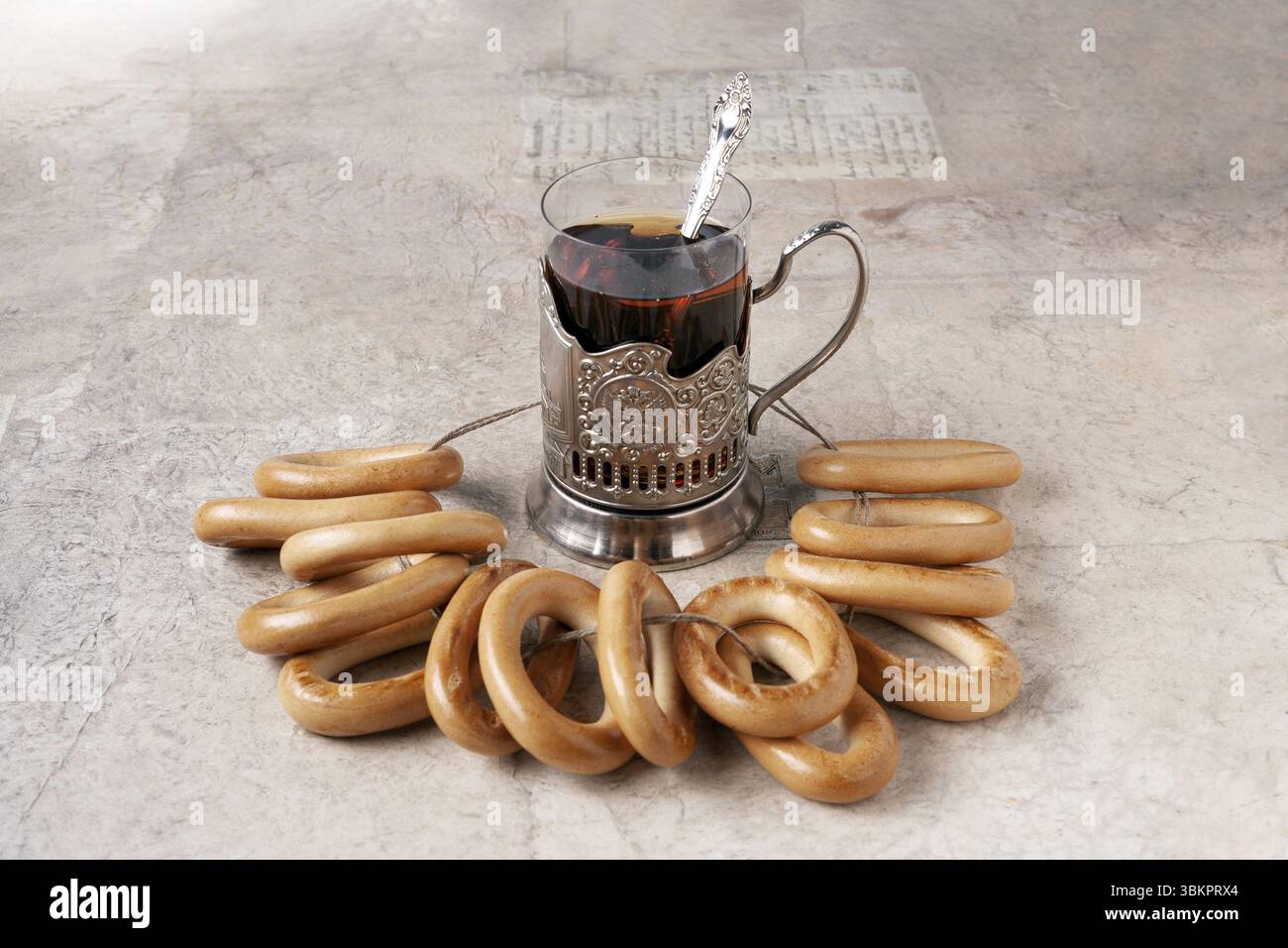 Un verre de thé dans un porte-gobelet en métal et un bouquet de bagels sur la table Banque D'Images