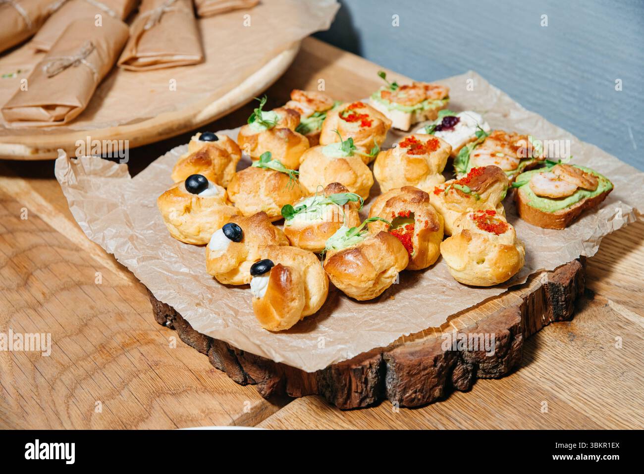 Sélection de pâtisseries salées, canapés et crostini avec garnitures comme crème, crevettes et caviar servis sur un plateau en bois. Banque D'Images