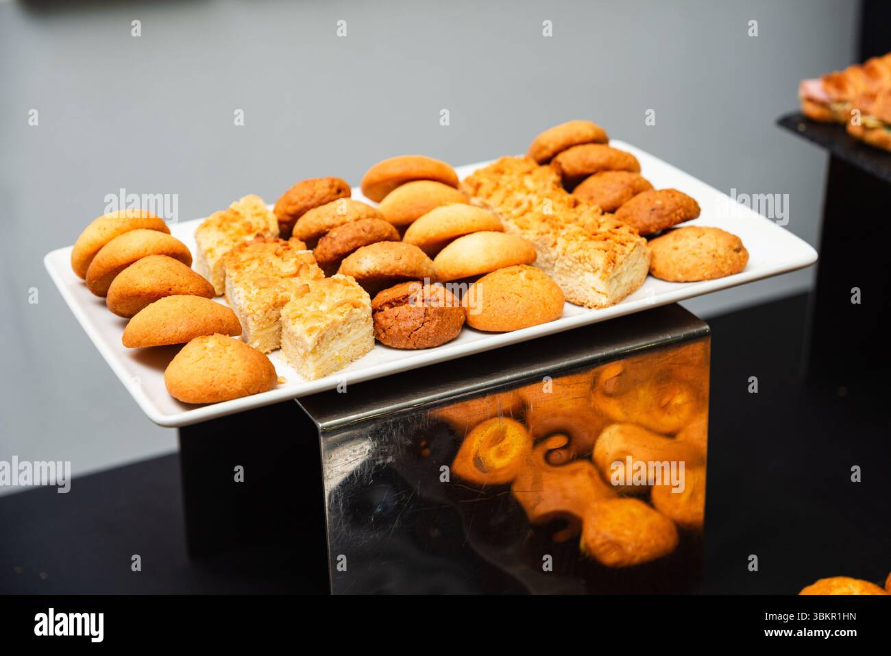 Une variété de biscuits et de pâtisseries affichés sur un plateau de service rectangulaire blanc, parfait pour la restauration ou les buffets de desserts. Banque D'Images