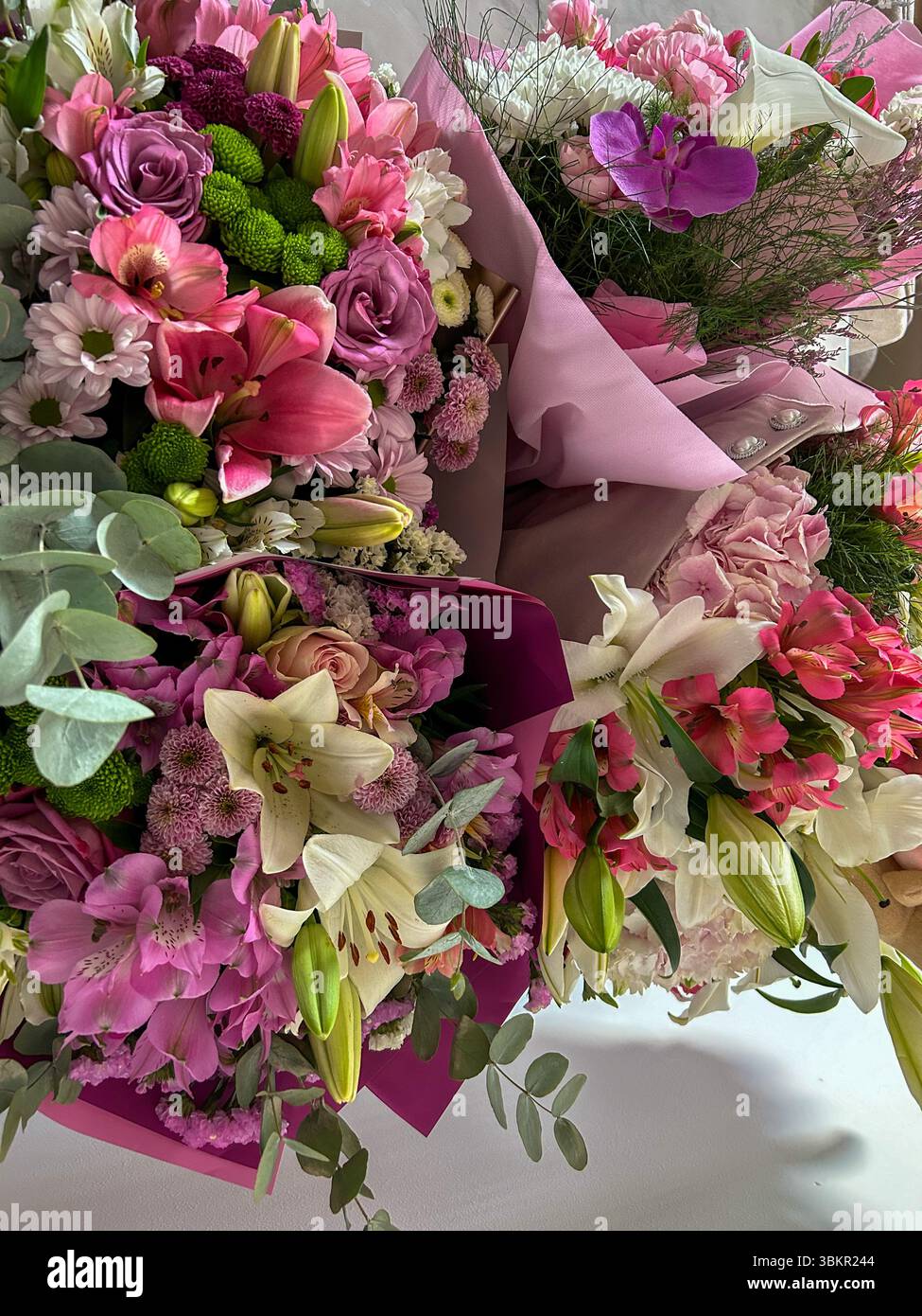 Arrangements floraux vibrants avec lys roses et blancs, roses, chrysanthèmes et orchidées, enveloppés dans du papier doux, idéal pour les mariages et les cadeaux. - Image de stock capturée avec un smartphone Arrangements floraux vibrants avec lys roses et blancs, roses, chrysanthèmes et orchidées, enveloppés dans du papier doux, idéal pour les mariages et les cadeaux. - Image de stock capturée avec un smartphone