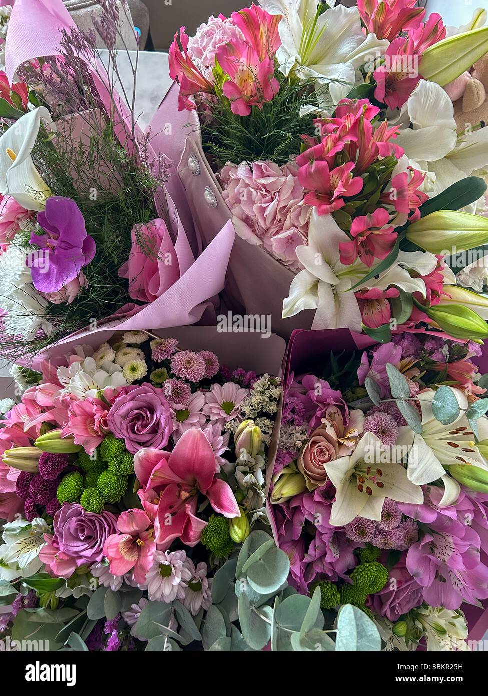 Bouquets de fleurs magnifiquement arrangés avec des lis, des roses, des orchidées, des chrysanthèmes et de la verdure dans des tons roses et blancs doux, parfait pour les célébrati - Image de stock capturée avec un smartphone