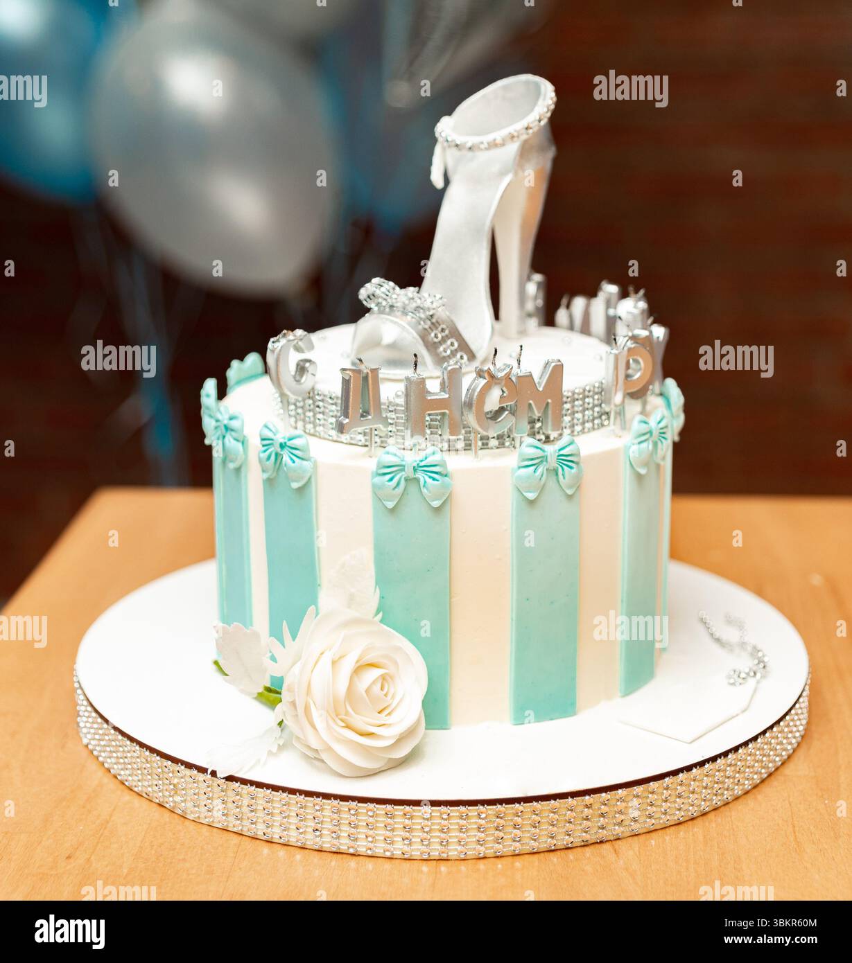 Gâteau décoratif avec un haut talon argenté, des rayures bleues pastel et rose blanche, parfait pour les anniversaires ou les fêtes de mariée. Banque D'Images