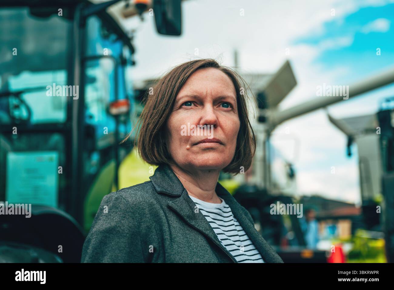 Femme entrepreneure agroalimentaire posant devant un véhicule de machines agricoles, focalisation sélective Banque D'Images