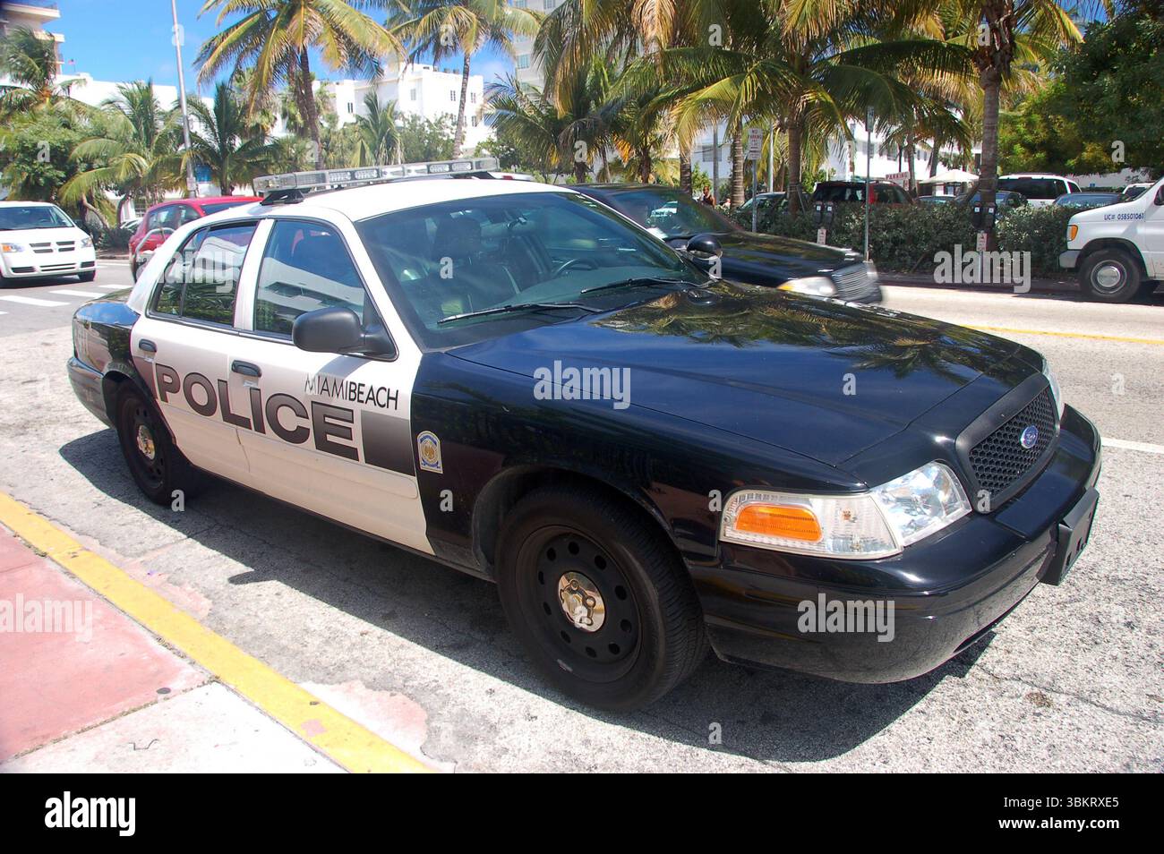 Voiture de police de Miami Beach garée dans une rue ensoleillée bordée de palmiers, montrant la présence des forces de l'ordre locales dans un cadre urbain tropical Banque D'Images