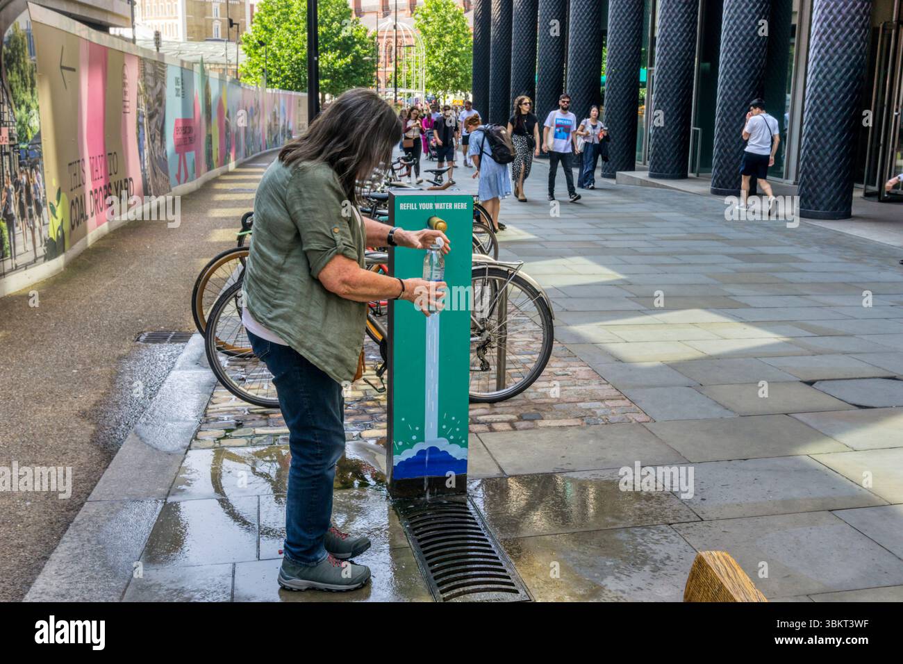 Femme remplissant une bouteille d'eau à un robinet public pendant une chaude journée à Londres. Banque D'Images