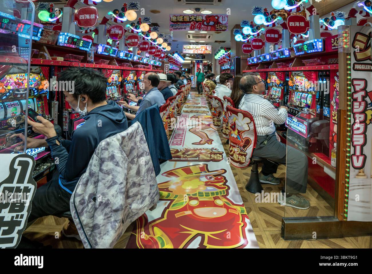 Les gens dans Pachinko jeu machine à sous arcade à Osaka, Japon. Le pachinko est un jeu populaire pour les loisirs et les jeux. Banque D'Images