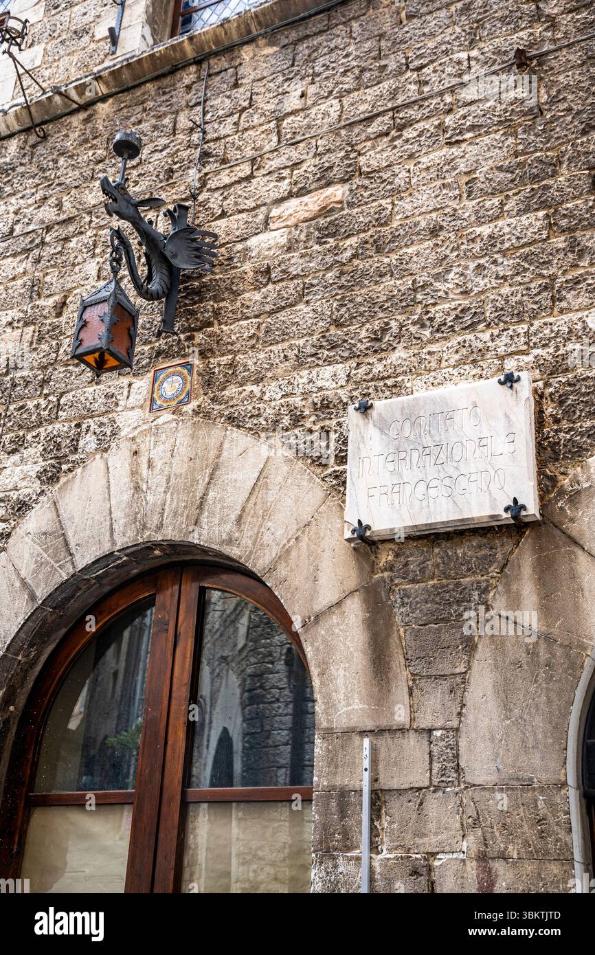 Lanterne décorative en fer forgé en forme de dragon sur un mur de pierre dans le centre historique médiéval d'assise, Ombrie, Italie Banque D'Images