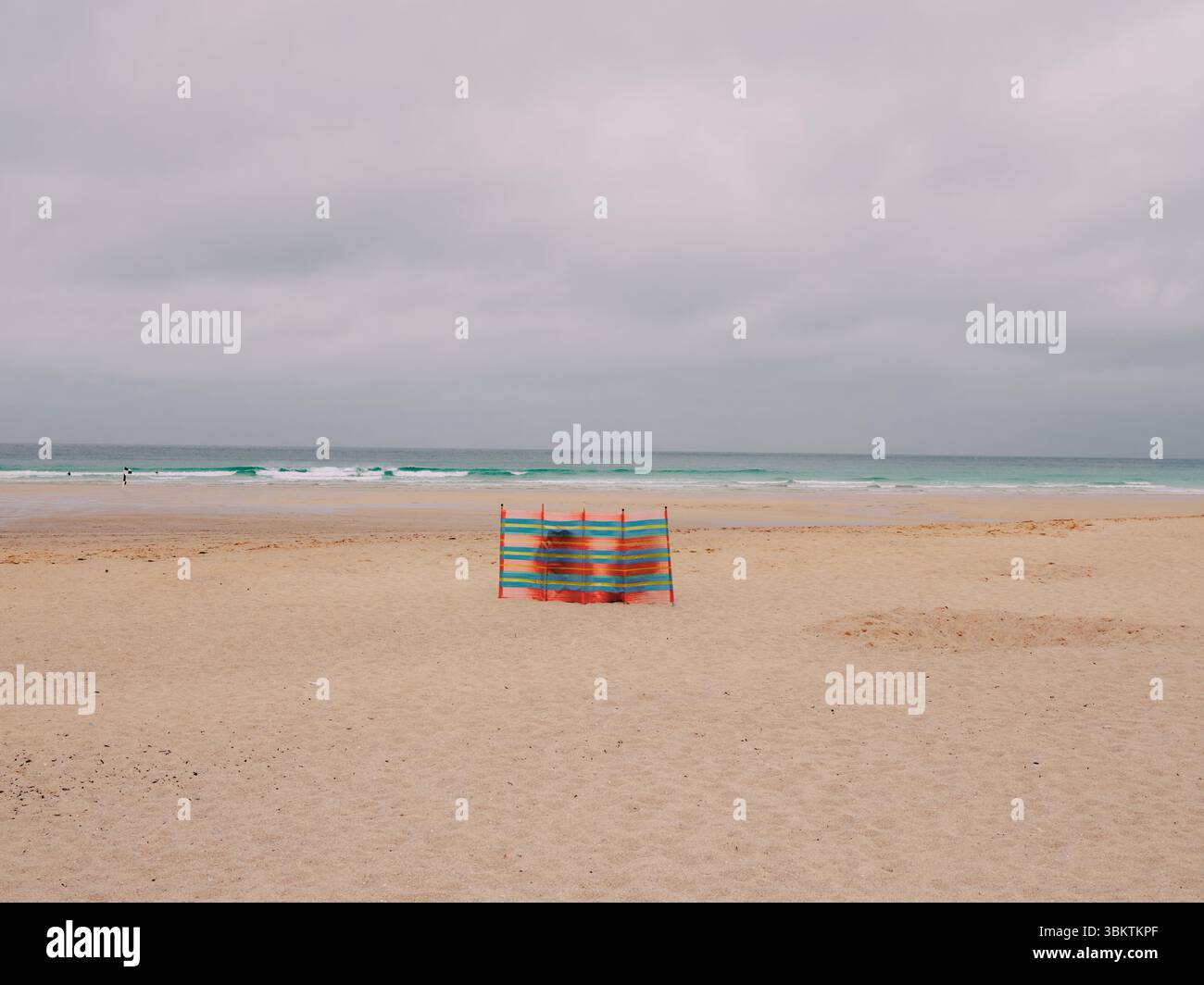 Un brise-vent solitaire sur une plage de sable nuageux vide en Cornouailles Angleterre Royaume-Uni - staycation UK vacances plage d'été étrange vie britannique excentrique Banque D'Images