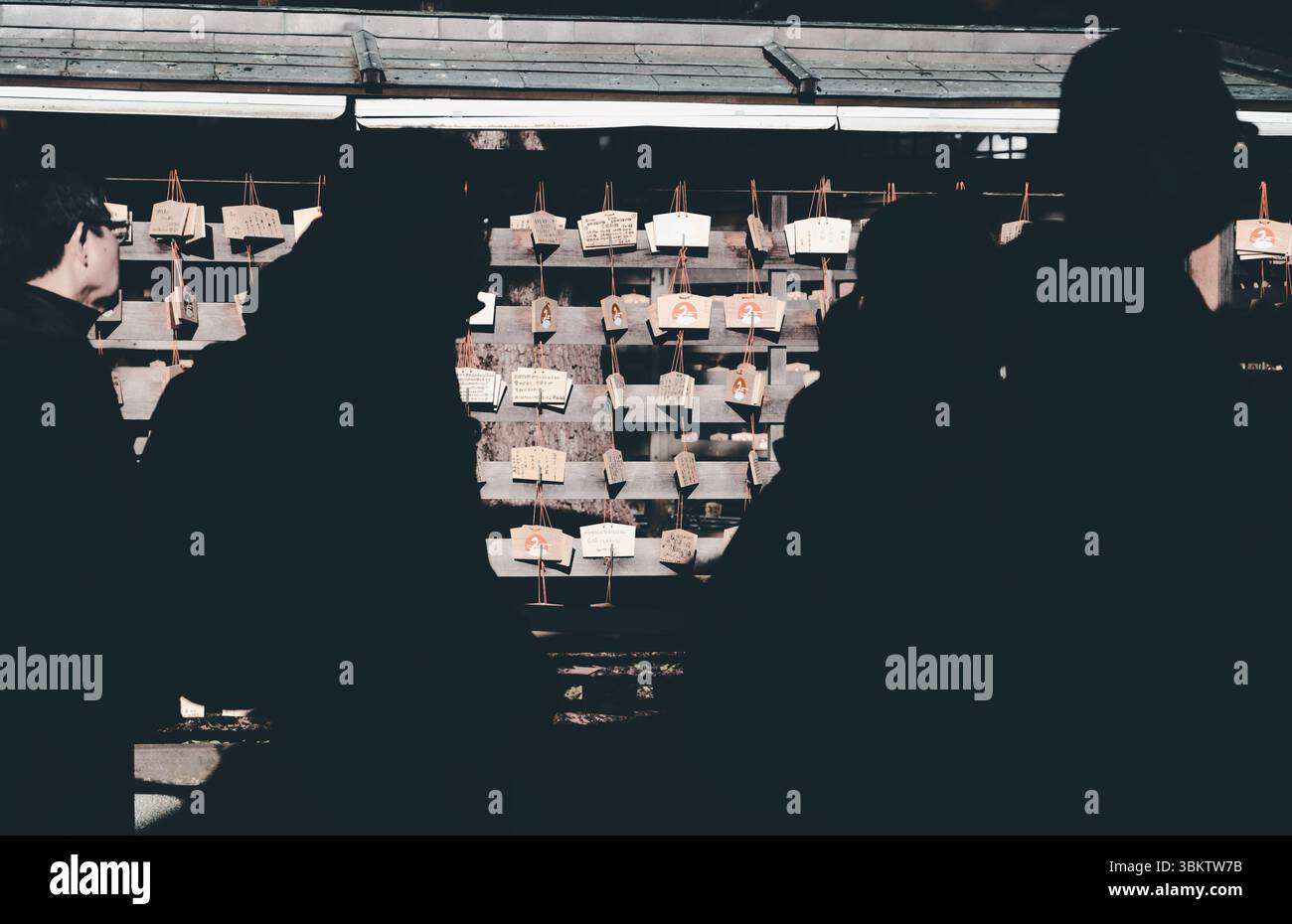 Les visiteurs passent devant des plaques de prière EMA au sanctuaire Meiji Jingu, où les souhaits et espoirs personnels pour la nouvelle année sont laissés dans la dévotion Banque D'Images