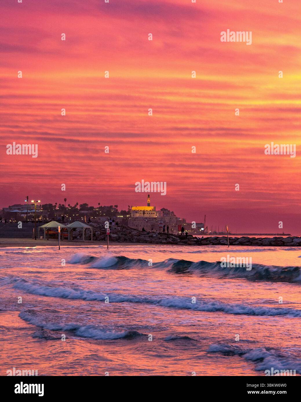 Beau coucher de soleil ardent sur une plage de la mer Méditerranée à tel Aviv Israël regardant vers la ligne d'horizon du vieux Yaffo (Jaffa) Banque D'Images