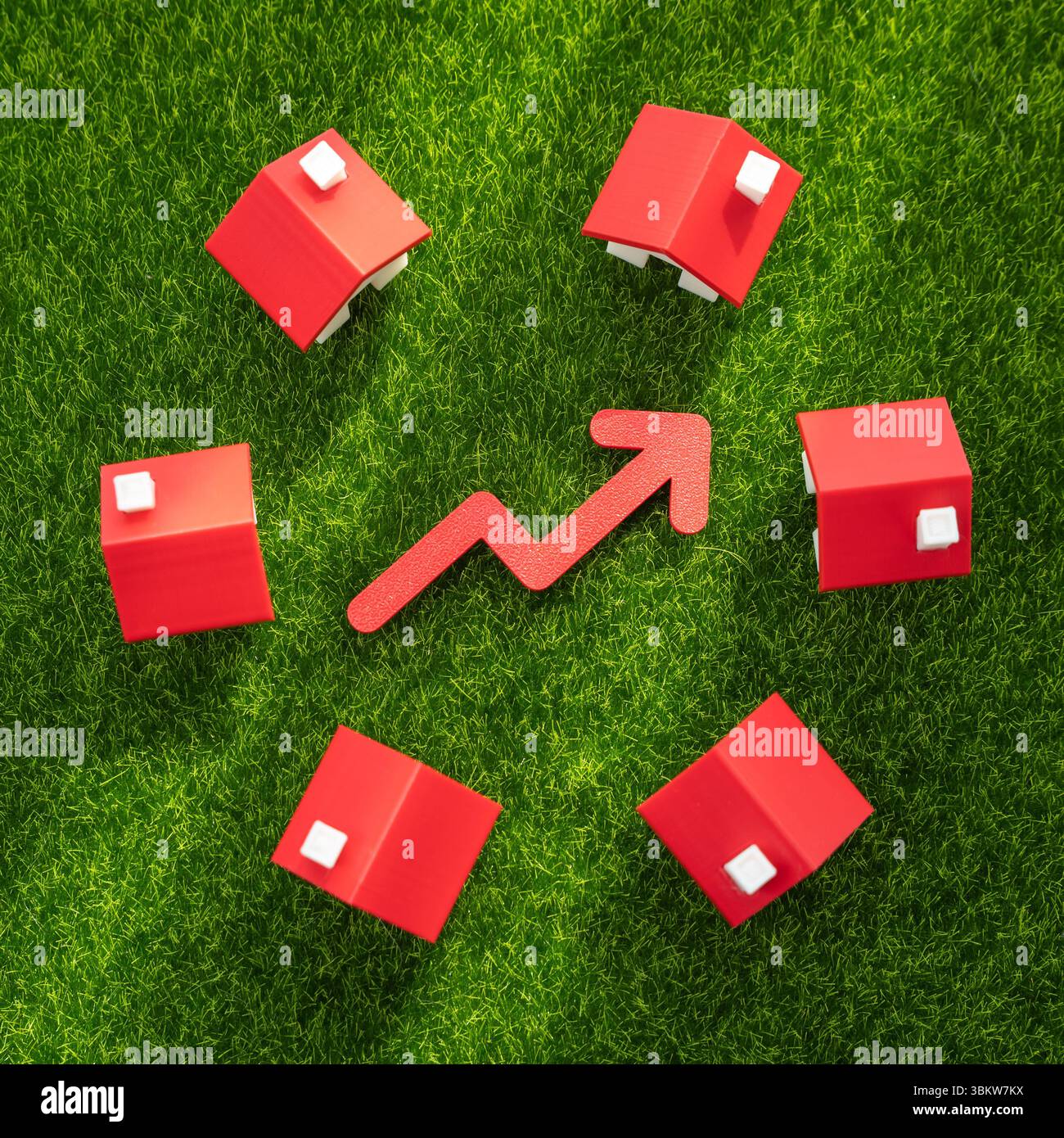 Maisons sur l'herbe et une flèche rouge pointant vers le haut. Hausse des prix du logement, croissance du marché ou augmentation de la demande de vie en banlieue. Immobilier apprécie Banque D'Images