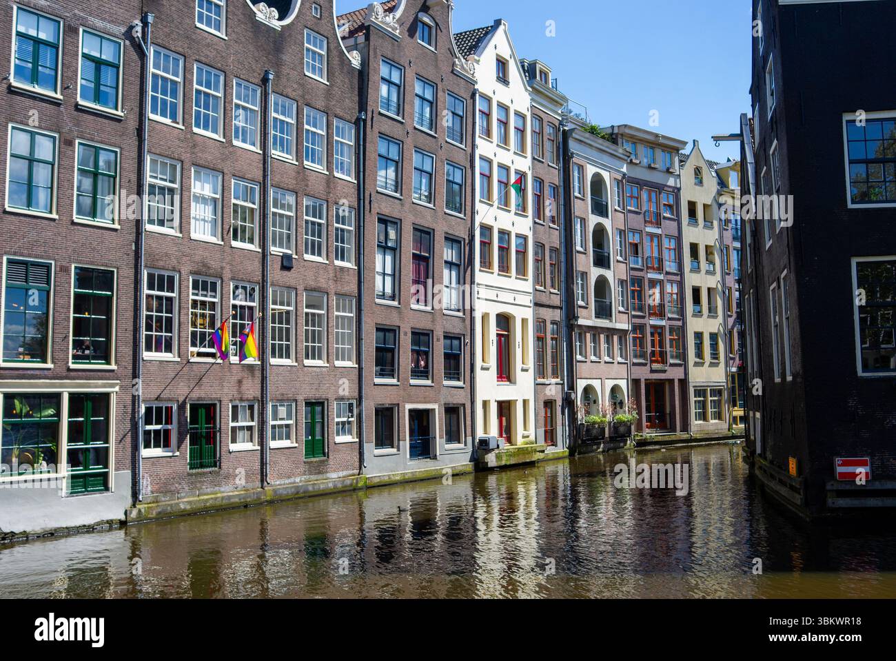Les maisons de canal classiques d'Amsterdam bordent l'eau, reflétant une journée ensoleillée. Banque D'Images