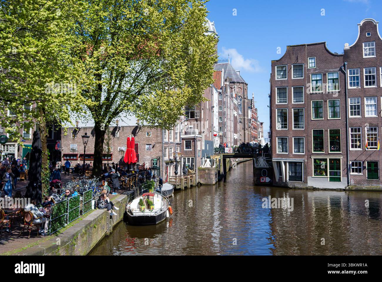 Les gens se détendent dans les cafés au bord du canal et profitent de la journée ensoleillée à Amsterdam. Banque D'Images