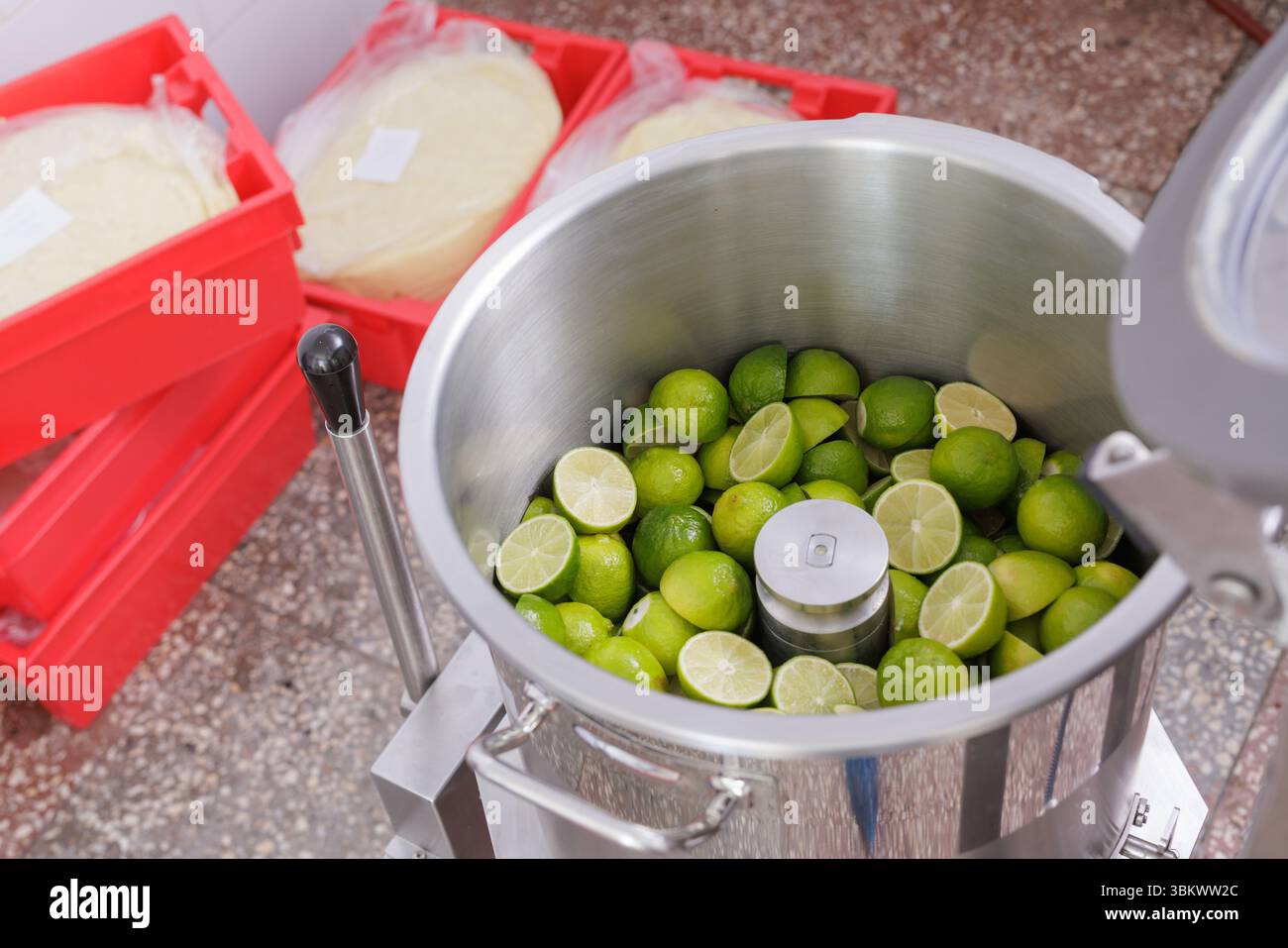 Limes fraîches traitées dans une machine à jus commerciale pour la production d'aliments et de boissons dans une cuisine moderne Banque D'Images