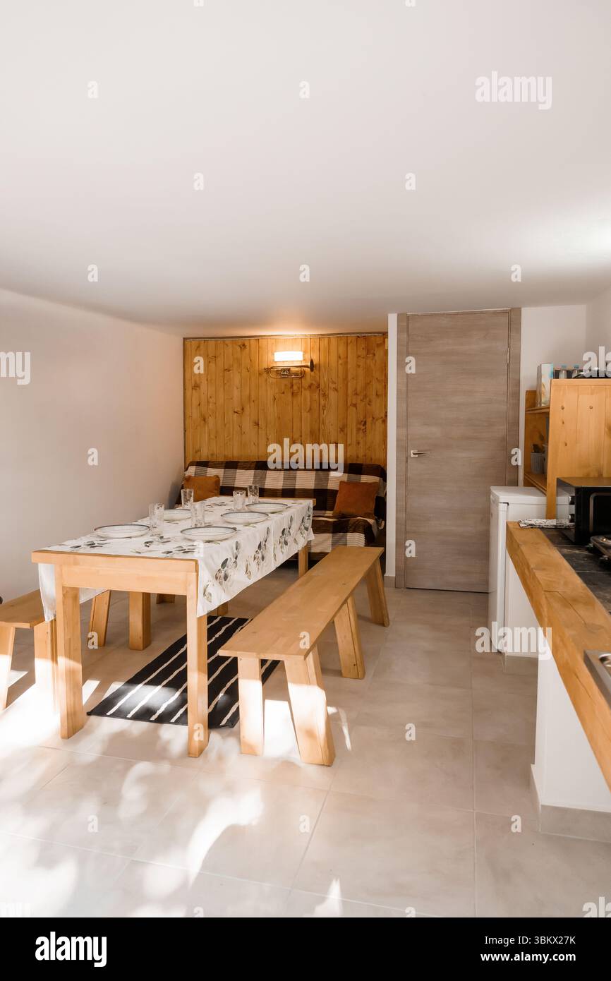 Une salle à manger lumineuse et accueillante dispose d'un mur d'accent en bois, d'une table couverte de nappe blanche et d'une banquette intégrée, idéale pour les repas en famille Banque D'Images