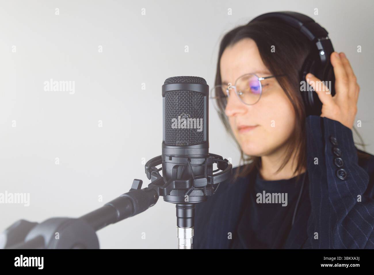 Jeune femme caucasienne en studio avec microphone et écouteurs. Banque D'Images