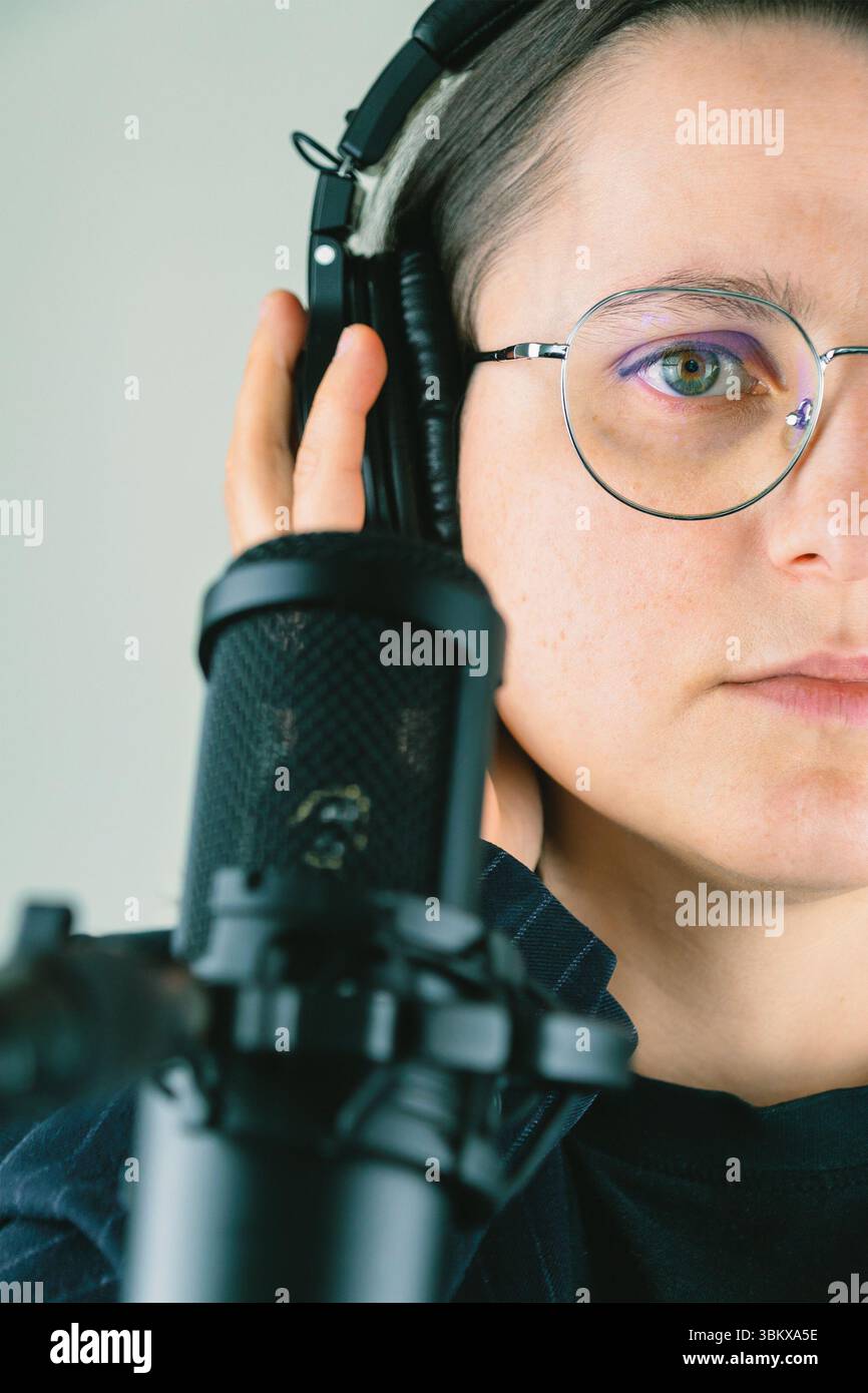 Podcast d'enregistrement adulte féminin en studio avec écouteurs et microphone. Banque D'Images