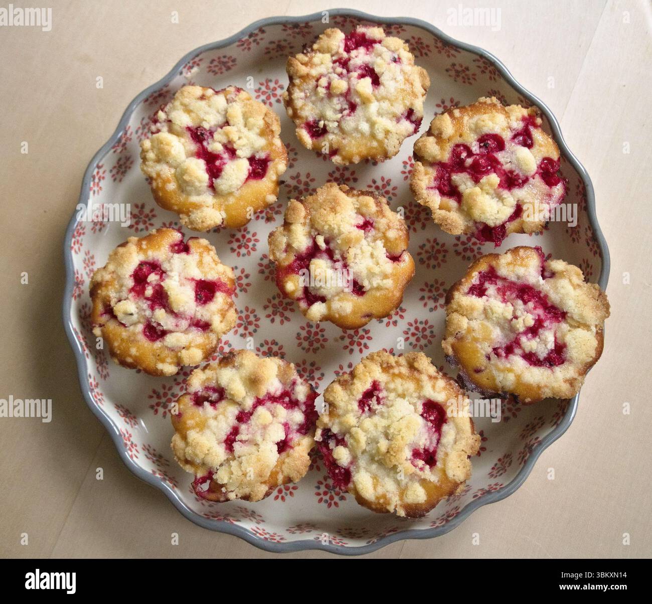 Vue de haut en bas de muffins aux baies faits maison dans un plat floral placé sur une table en bois rustique. Banque D'Images