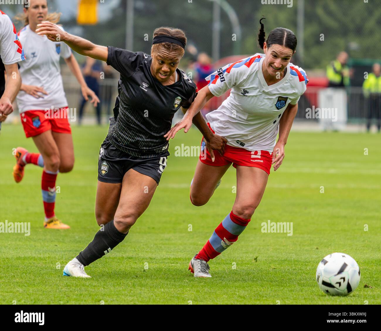 BURNABY, CANADA – 23 JUIN 2025 : L’attaquante du Vancouver Rise FC Mariah Lee (no 9, maillot noir) se bat pour la possession avec un défenseur du Montreal Roses FC lors d’un match intense de Super League du Nord (NSL) au Swangard Stadium. Le duel sur le terrain met en valeur la compétition physique de haut calibre qui définit la saison inaugurale de la nouvelle ligue professionnelle de soccer féminin du Canada. Crédit : Joe Ng/Alamy Live News Banque D'Images