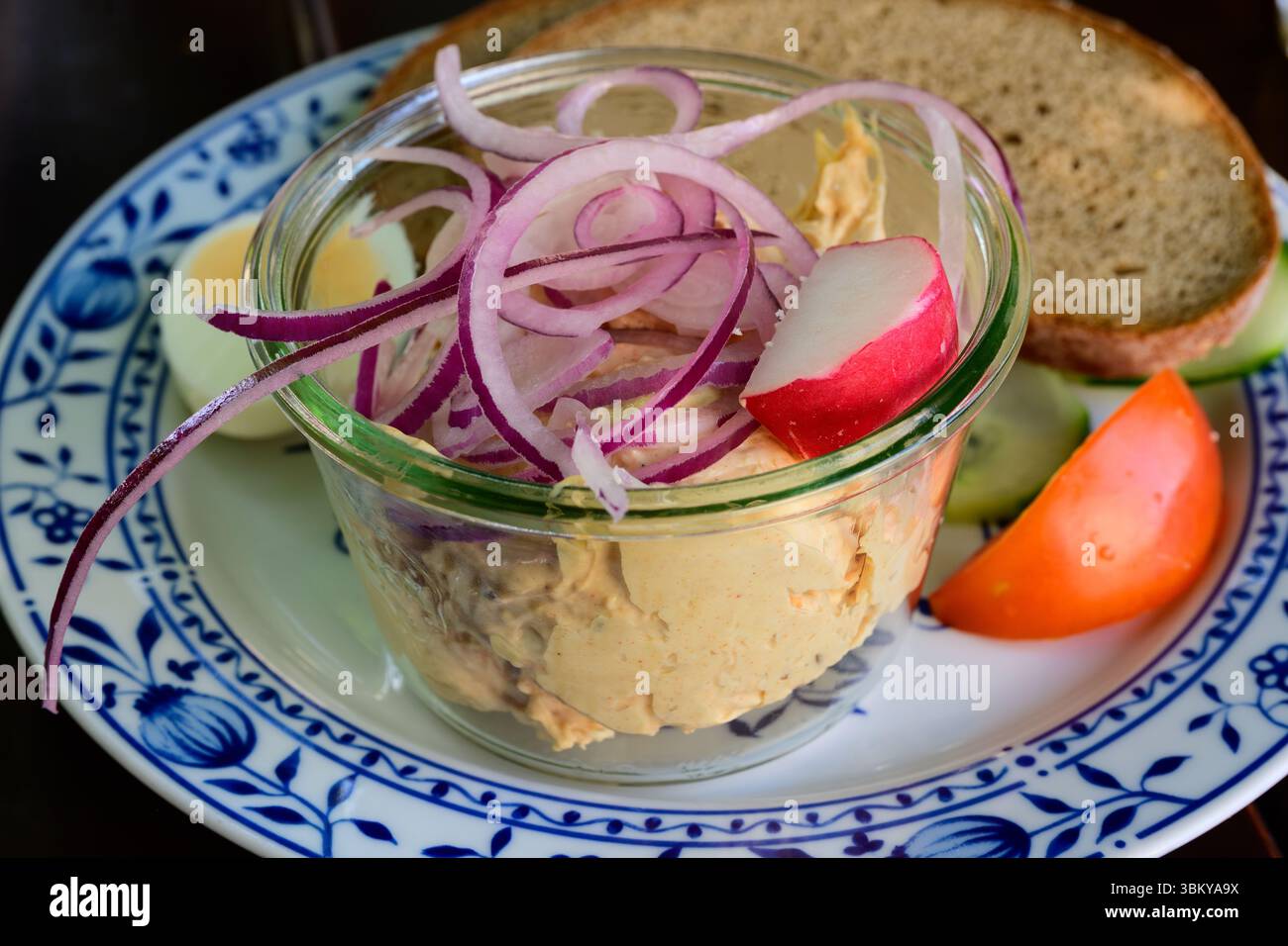 Tartinade au fromage bavarois Obatzda, Obazda ou Obatzter garnie d'oignons dans un bol et de pain en gros plan Banque D'Images