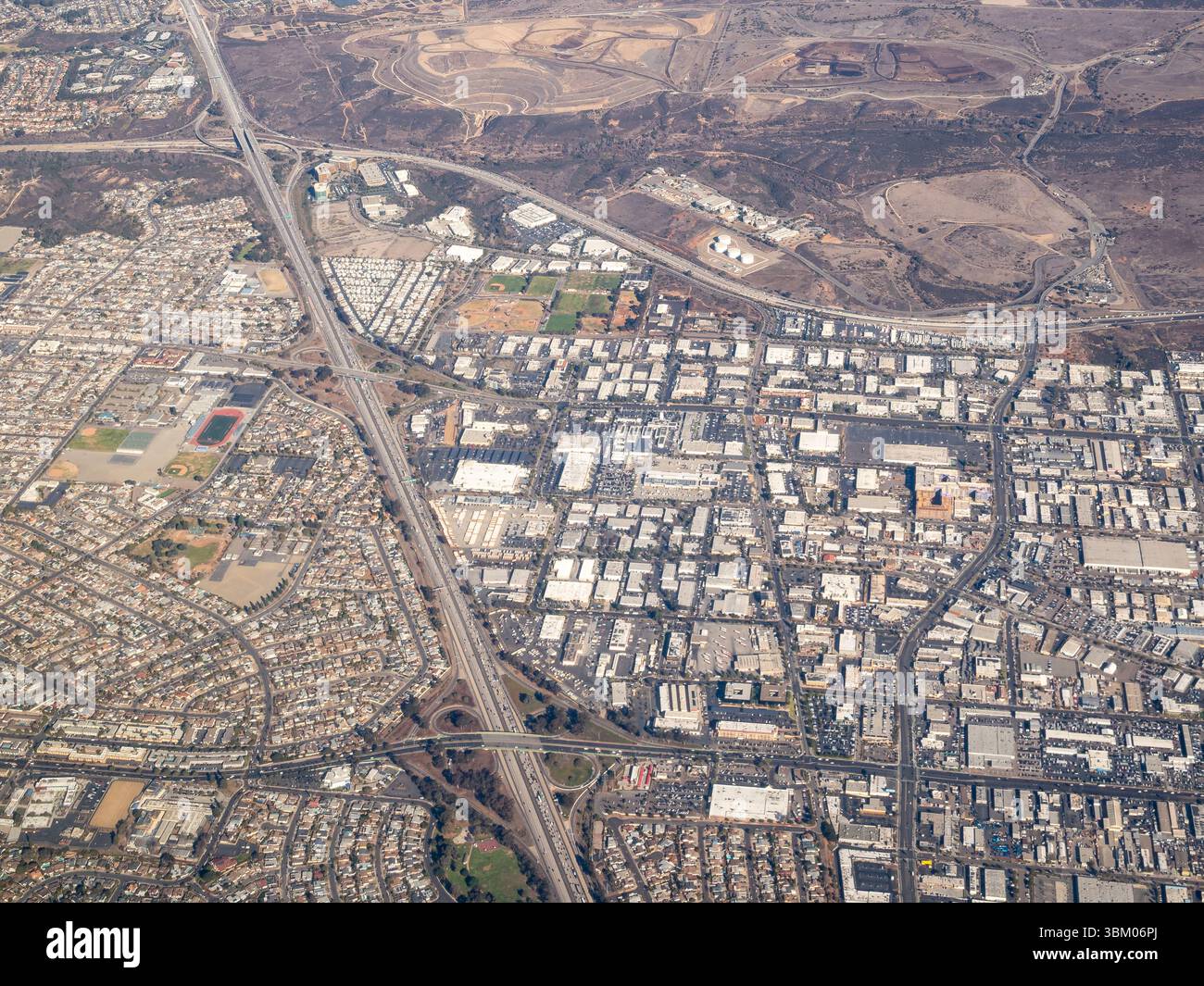 Cette photo aérienne capture le paysage urbain d'une ville, mettant en valeur un mélange de zones résidentielles, de bâtiments commerciaux et de zones industrielles, tous reliés par un réseau d'autoroutes et de routes, mettant en évidence l'infrastructure et le développement de la ville. Banque D'Images