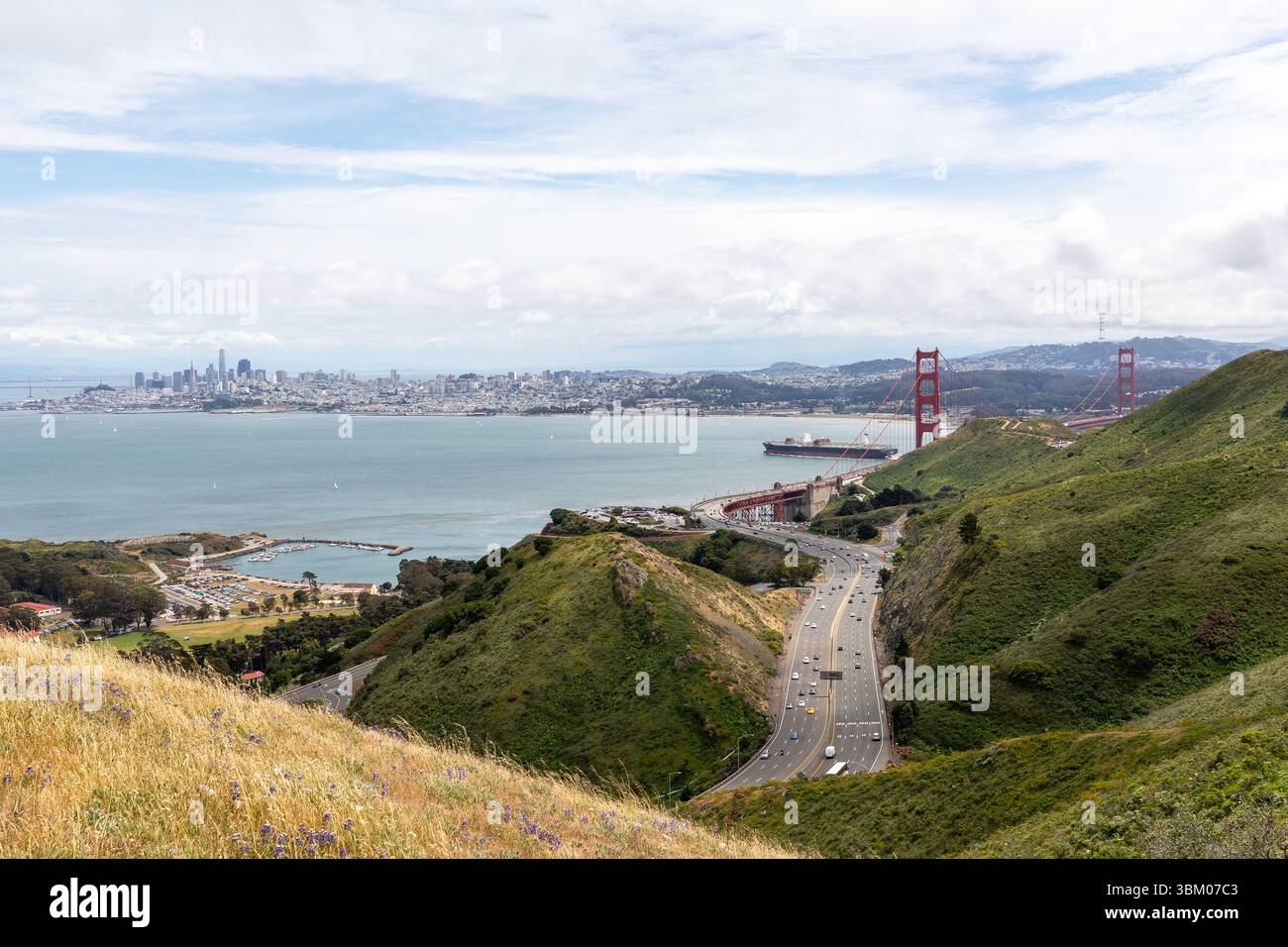 Une vue panoramique sur le Golden Gate Bridge, les gratte-ciel de San Francisco et une autoroute très fréquentée serpentant à travers les collines, mettant en valeur les monuments emblématiques de la ville et les infrastructures de transport. Banque D'Images Une vue panoramique sur le Golden Gate Bridge, les gratte-ciel de San Francisco et une autoroute très fréquentée serpentant à travers les collines, mettant en valeur les monuments emblématiques de la ville et les infrastructures de transport. Banque D'Images