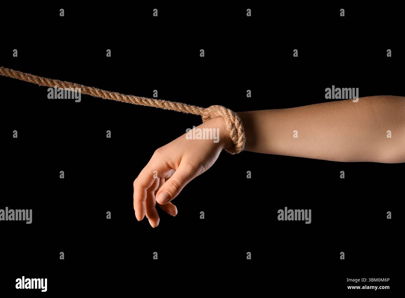 Main avec corde sur fond noir. Concept d'oppression Banque D'Images