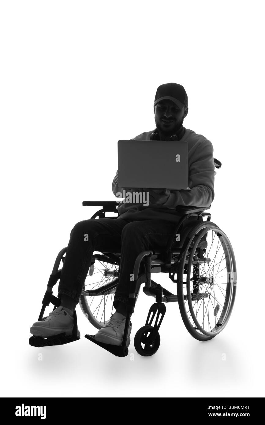 Silhouette de jeune homme en fauteuil roulant à l'aide d'un ordinateur portable sur fond blanc Banque D'Images Silhouette de jeune homme en fauteuil roulant à l'aide d'un ordinateur portable sur fond blanc Banque D'Images