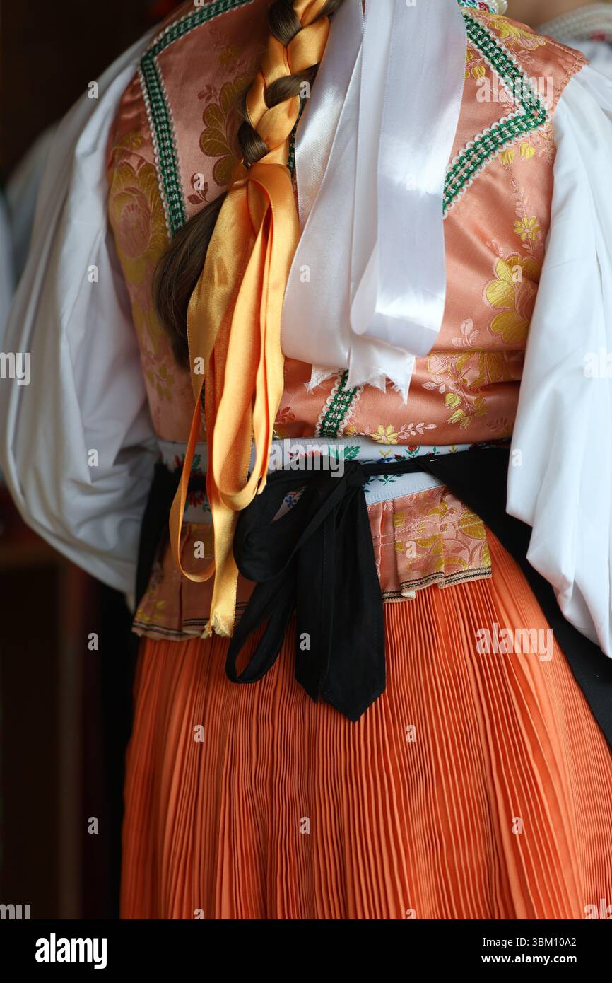 Vue arrière du costume folklorique tchèque traditionnel avec jupe plissée orange et corsage brodé Banque D'Images