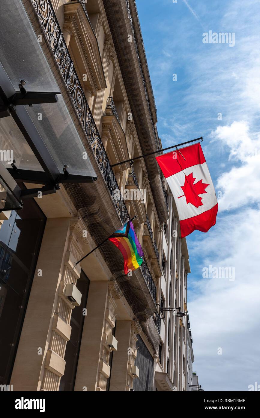 Paris, France, 06.23.2025. Le canadien et le nouveau drapeau de la fierté du progrès accroché à l'extérieur de l'ambassade du Canada dans le 8e arrondissement de Paris Banque D'Images